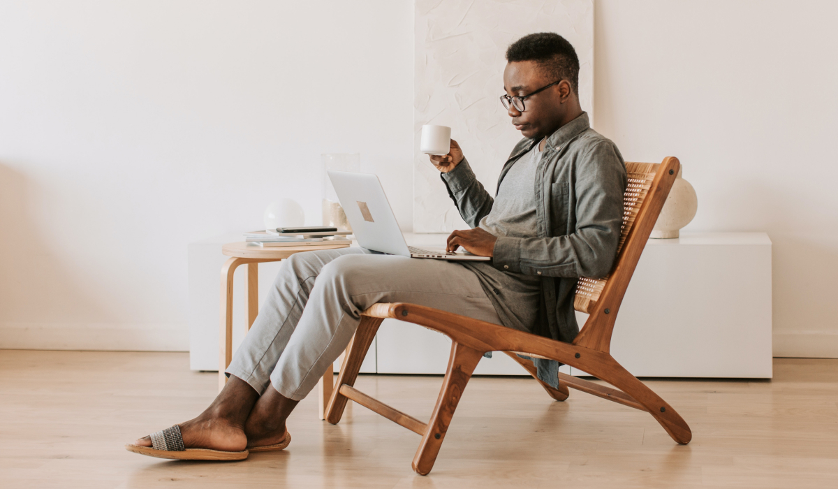 Homme sur son ordinateur avec un café dans les mains 