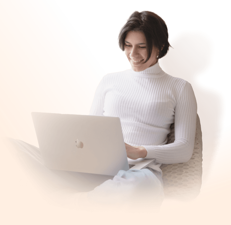 Une femme souriante naviguant sur son ordinateur
