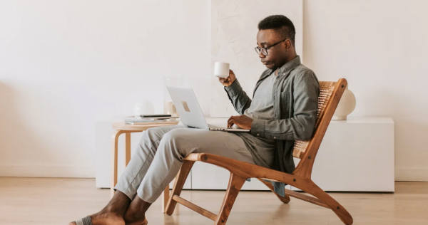 Man typing on his computer with a coffee in his hands