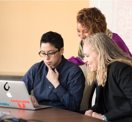 A happy team reviewing work on a computer